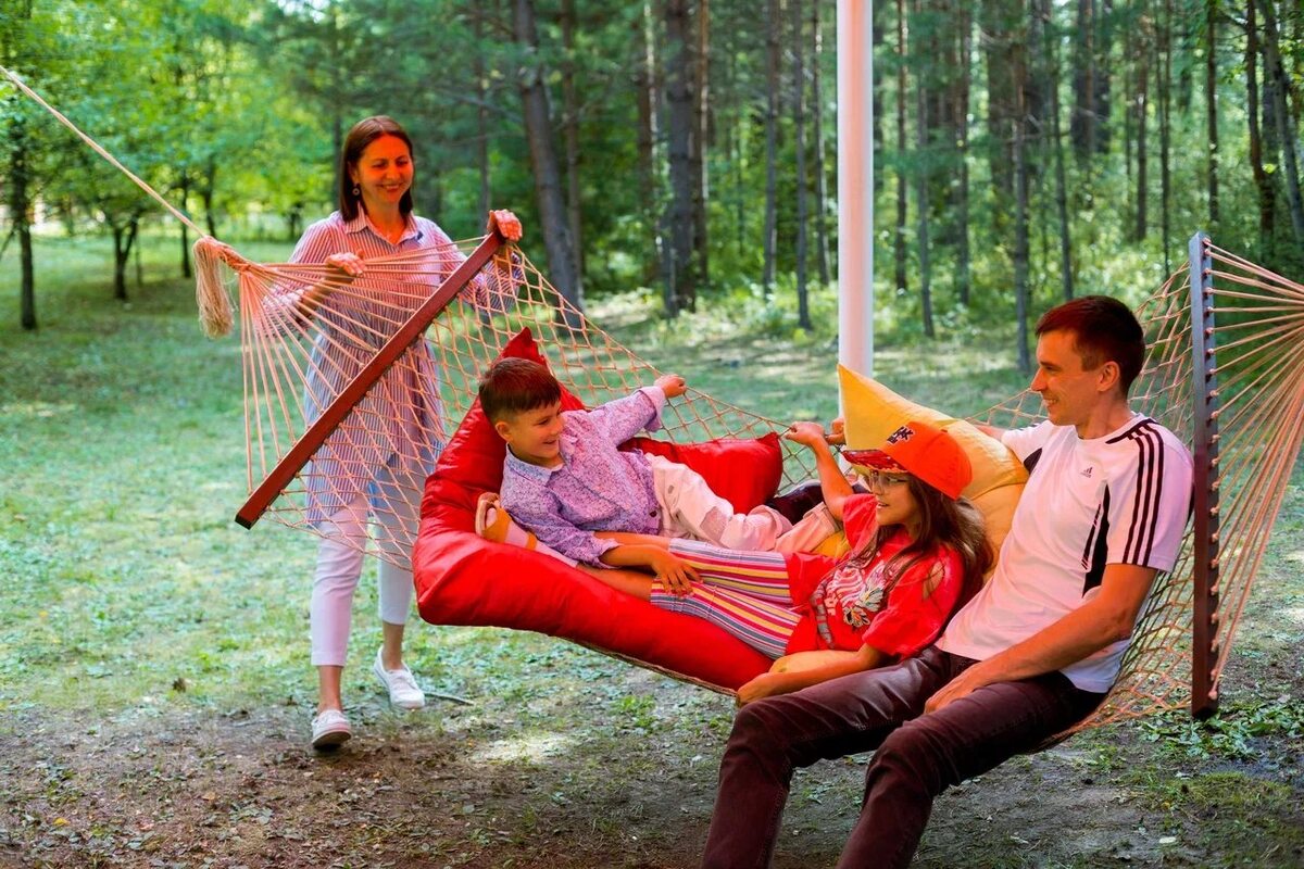Родители отдыхают в гамаках в сосновом бору